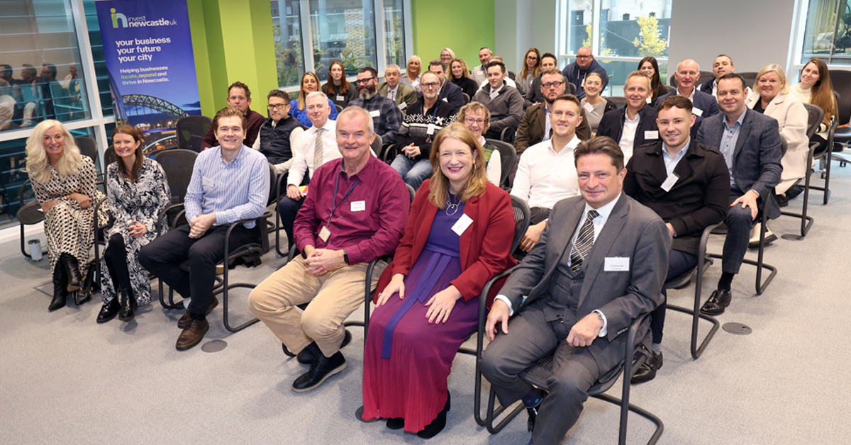 A group of executives sitting in rows of chairs and smiling towards the camera, at Invest Newcastle MIPIM Gathering