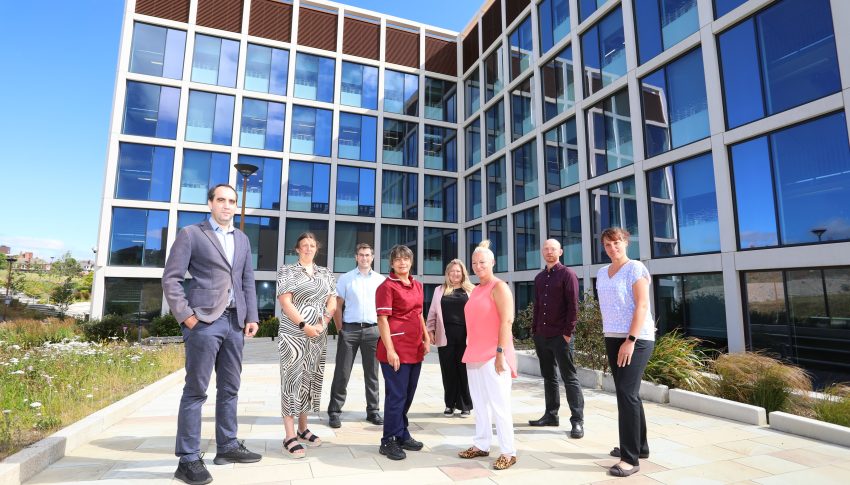 The lab team stood outside The Biosphere building in bright sunshine.