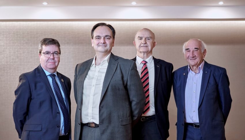 Group of four people from PulmoBioMed stood against bare wall smiling towards camera.